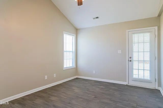 an empty room with wooden floor and windows