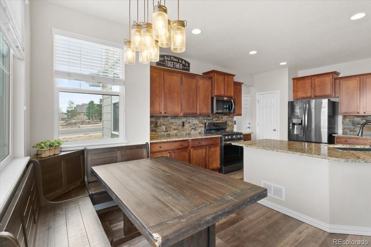 1906 Charbray Point Castle Rock, CO 80108 - Photo 14 of 44 a kitchen with stainless steel appliances granite countertop a stove a refrigerator a sink dishwasher a dining table and chairs with wooden floor