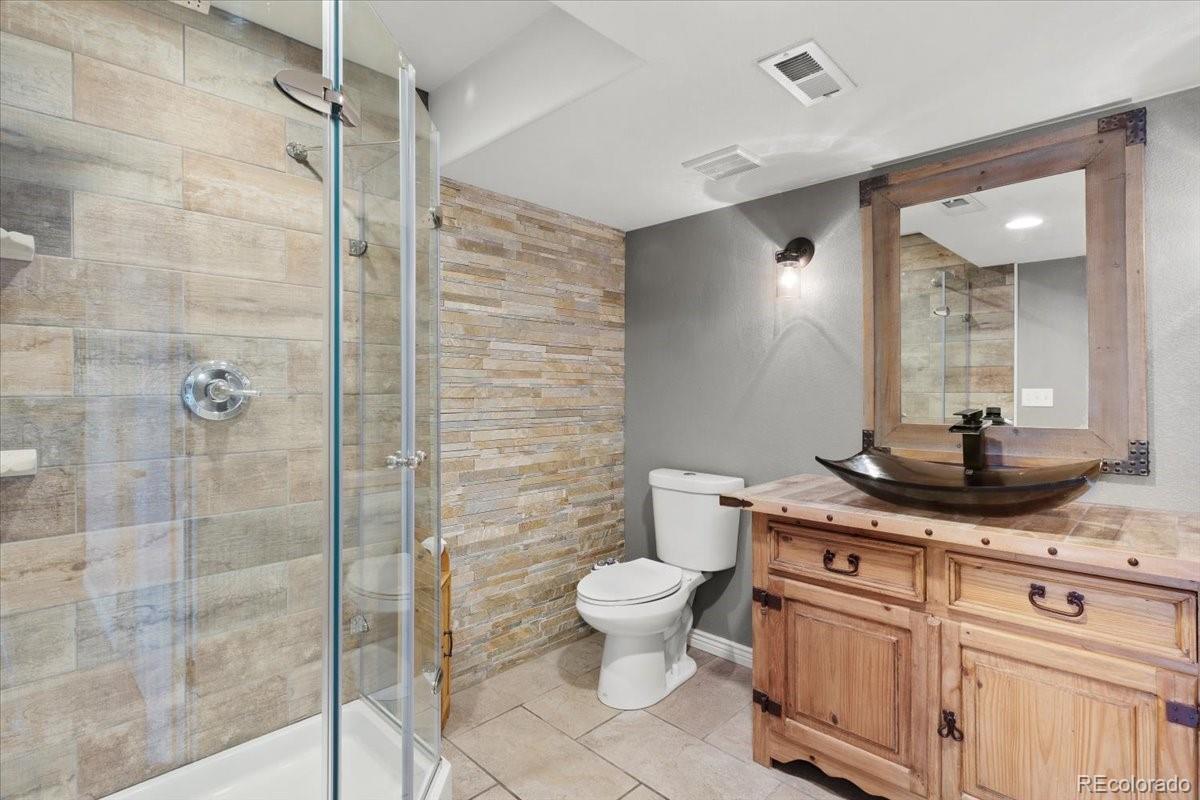 1906 Charbray Point Castle Rock, CO 80108 - Photo 35 of 44 a bathroom with a granite countertop sink a toilet a mirror and shower