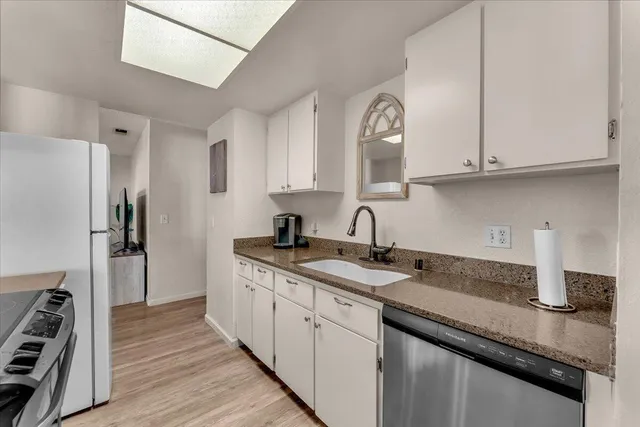 a kitchen with granite countertop a sink stainless steel appliances and cabinets