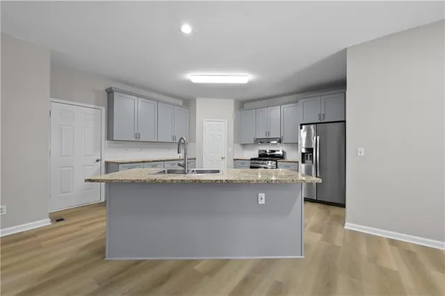 a kitchen with granite countertop a refrigerator stove top oven and sink