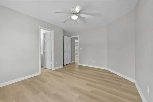 an empty room with ceiling fan and windows