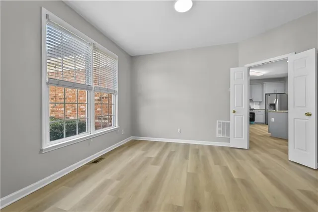 a view of empty room with wooden floor and fan