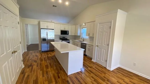 a large kitchen with stainless steel appliances a refrigerator a sink a stove and white cabinets