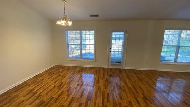 an empty room with wooden floor cabinet and windows