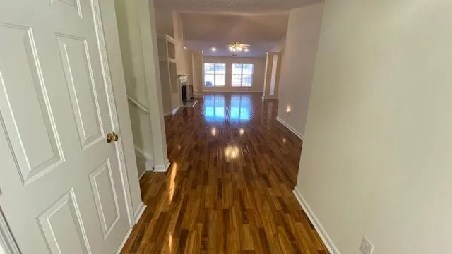 a view of empty room with wooden floor and fan