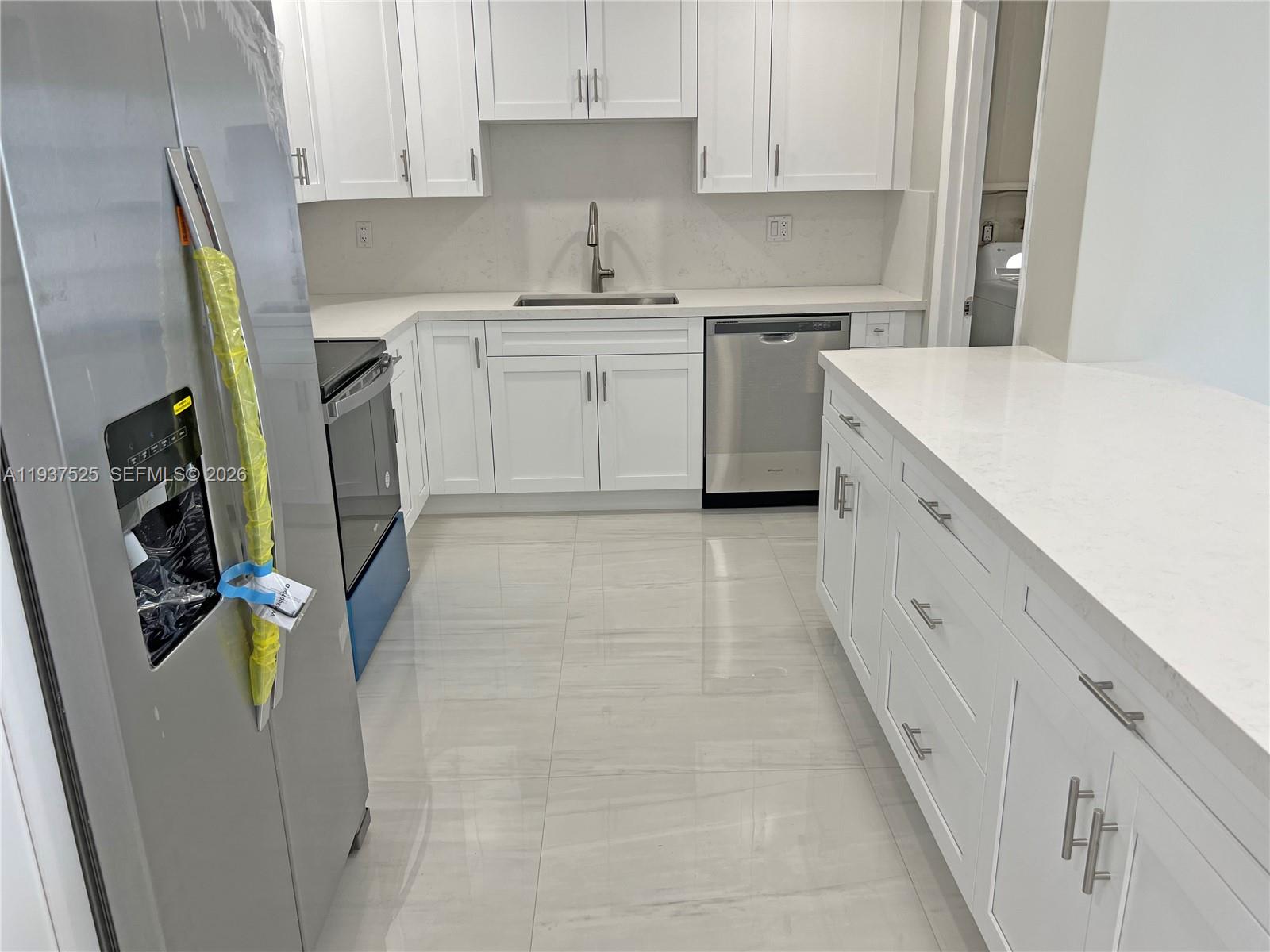 11962 Southwest 37th Terrace Miami, FL 33175 - Photo 9 of 24 a kitchen with stainless steel appliances a refrigerator sink and white cabinets