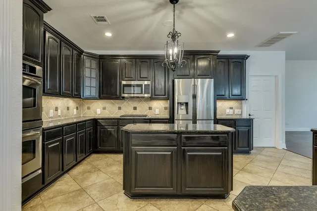 a kitchen with kitchen island granite countertop stainless steel appliances and wooden cabinets
