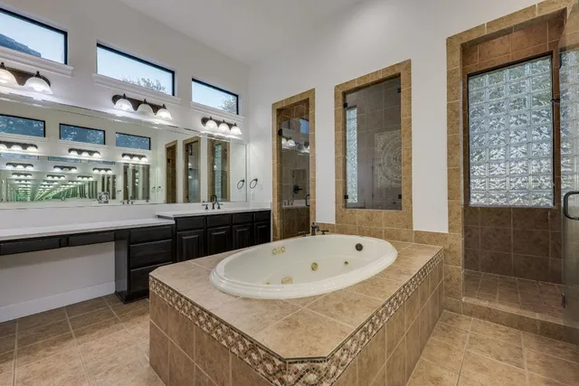 a bathroom with a tub a sink and a large mirror