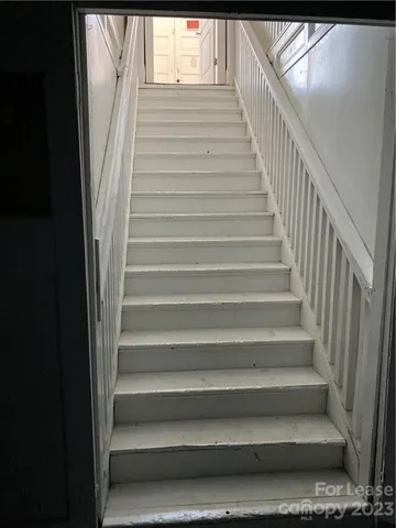 a view of an empty room with wooden floor and staircase