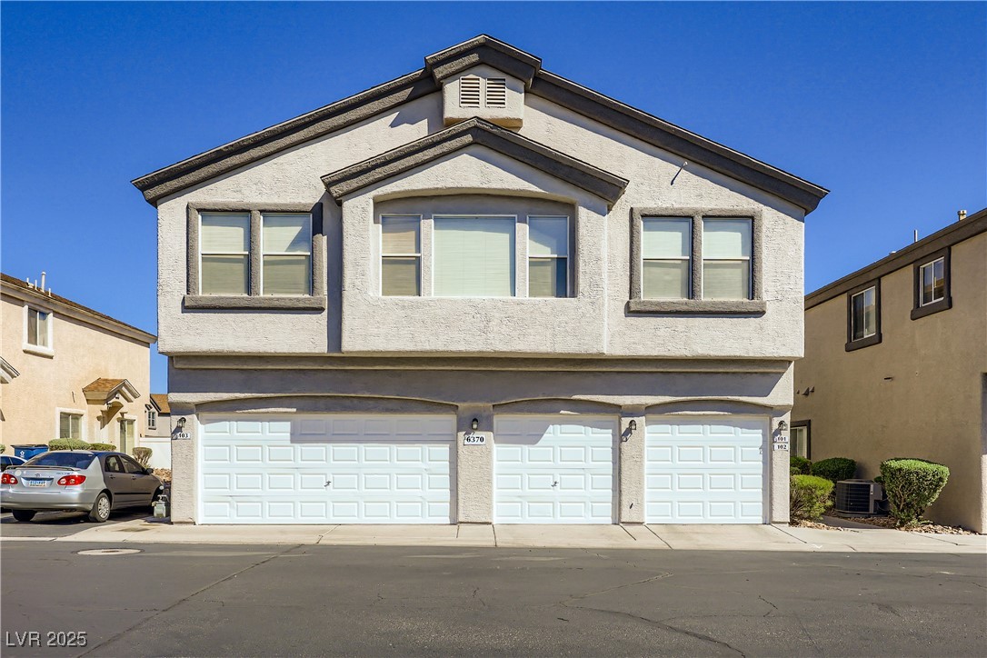 View of front of property featuring stucco siding, a garage, and driveway