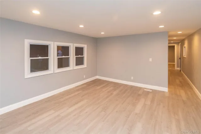 a view of empty room with wooden floor and windows