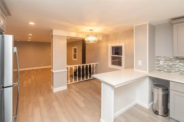 a view of a hallway with wooden floor and a kitchen