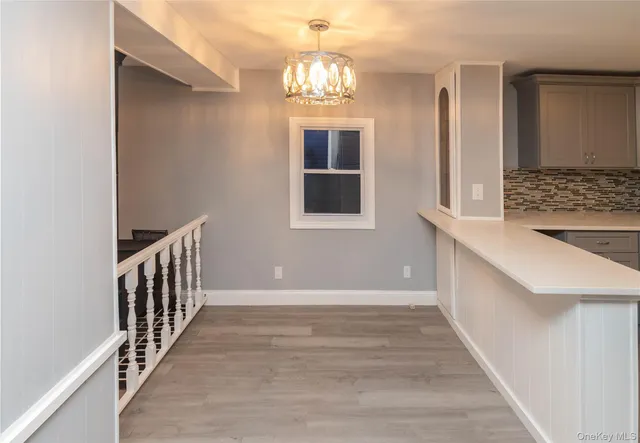 a view of a hallway with windows and chandelier