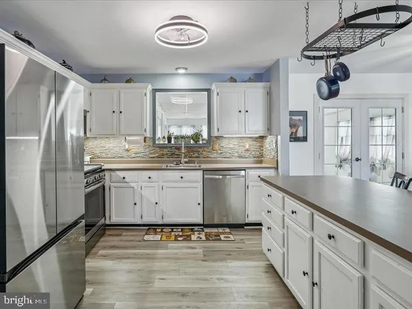 a living room with stainless steel appliances lots of furniture and wooden floors