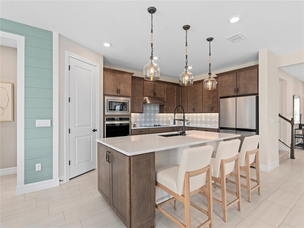 5624 Flame Vine Way St. Cloud, FL 34771 - Photo 12 of 29 a kitchen with stainless steel appliances kitchen island granite countertop a refrigerator a microwave oven a sink with island and chairs