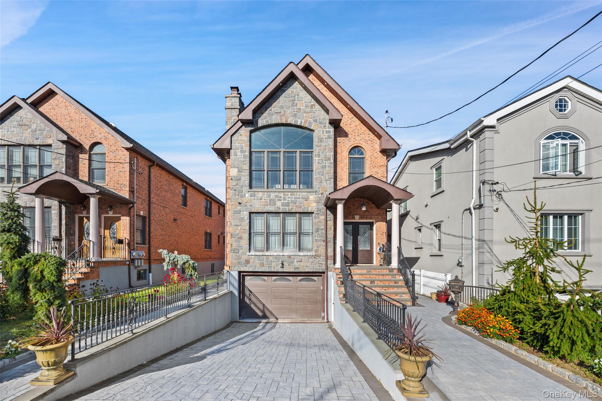 View of front of property featuring stone siding, decorative driveway, a garage, and a chimney