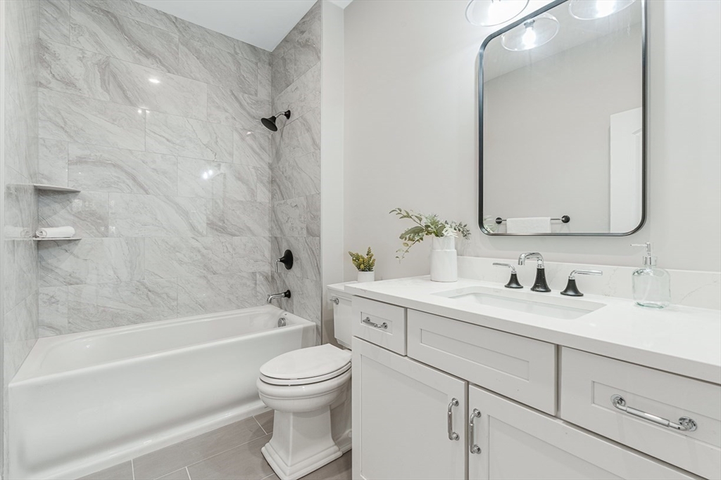 7 Crossman Road Woburn, MA 01801 - Photo 19 of 42 a bathroom with a bathtub shower sink vanity mirror and toilet