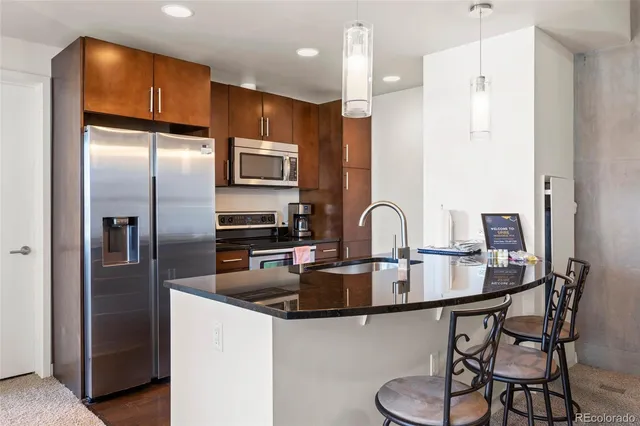 a kitchen with stainless steel appliances granite countertop a refrigerator a stove a sink and a microwave