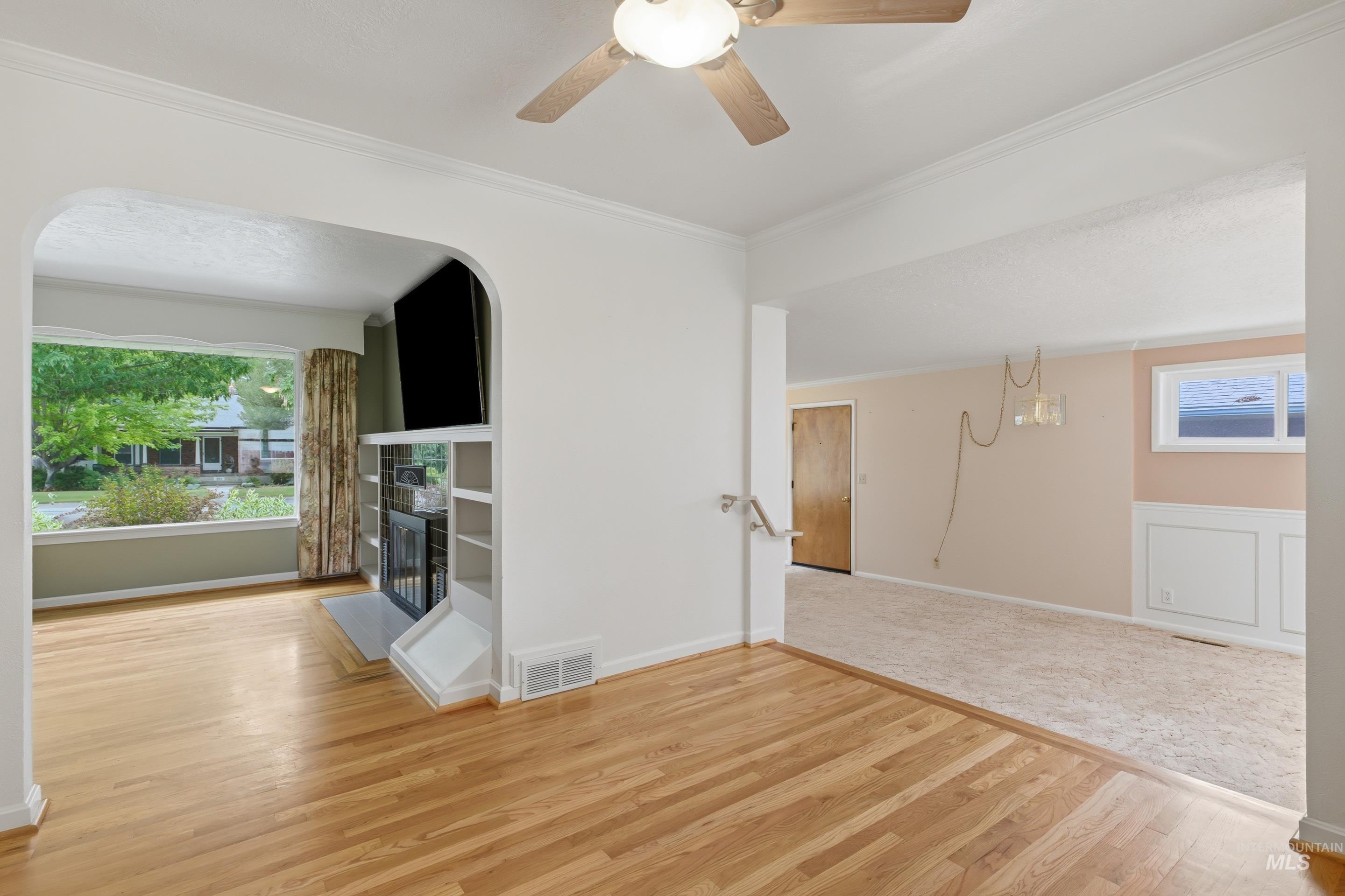 504 West Howe Street Boise, ID 83706 - Photo 10 of 47 Hardwood flooring extending into an arched entryway, featuring a built-in fireplace with shelving, and crown molding