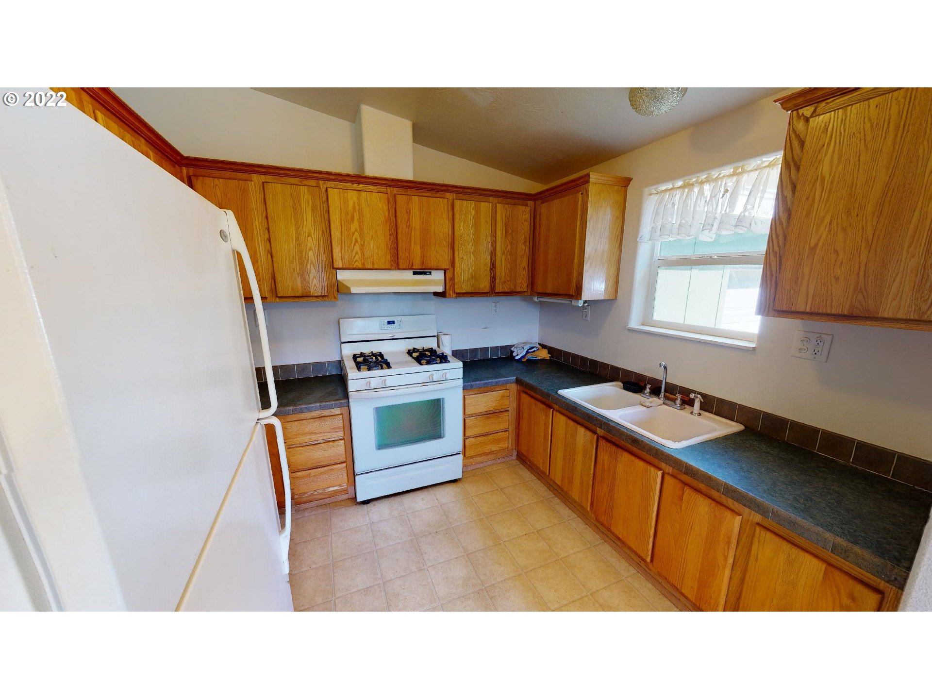 94635 Grange Road Gold Beach, OR 97444 - Photo 13 of 27 a kitchen with stainless steel appliances a sink a stove a refrigerator cabinets and a window