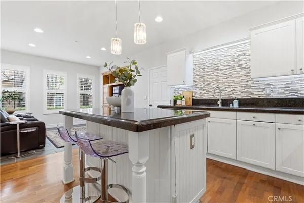 a kitchen with granite countertop a sink and white cabinets with wooden floor