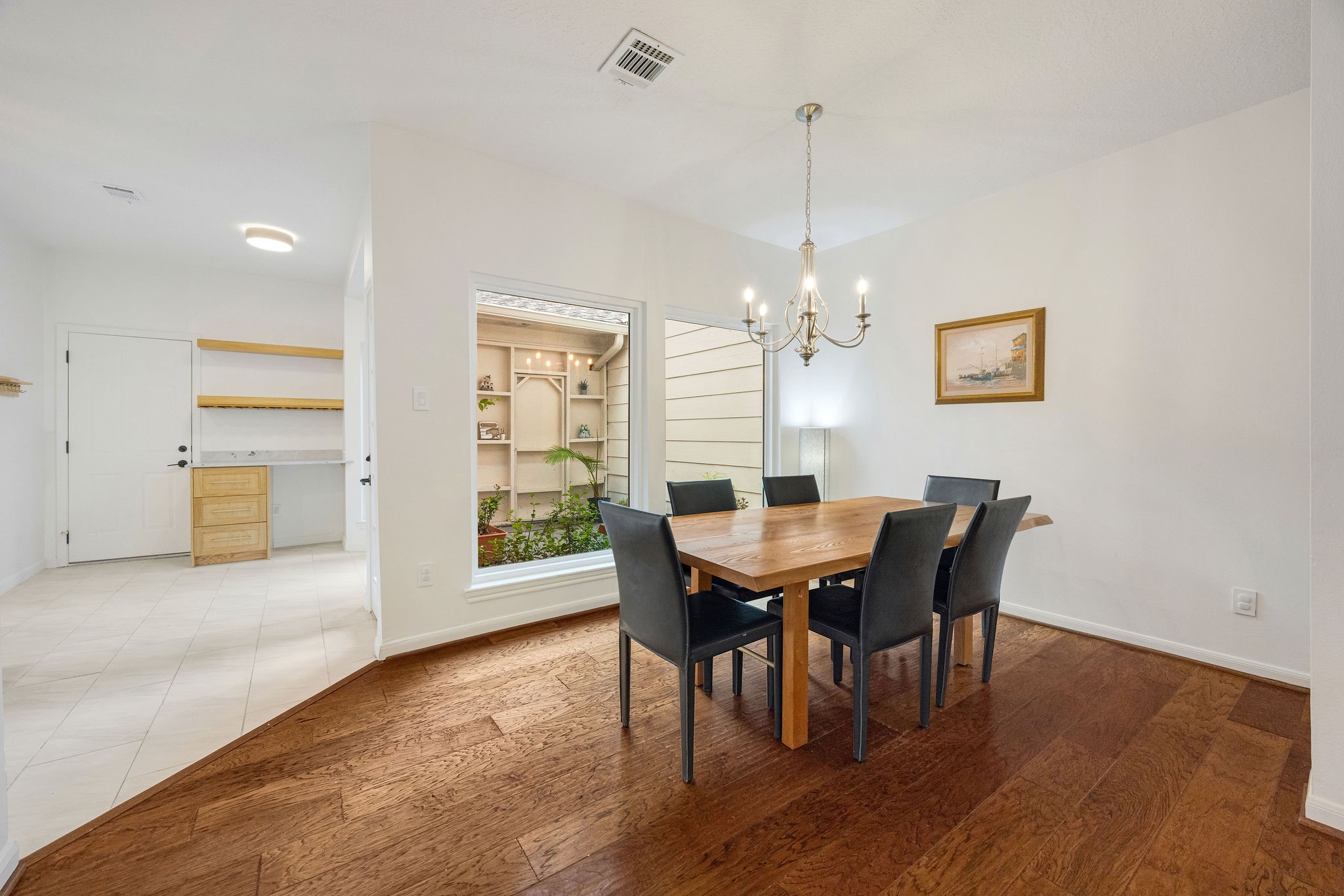 727 Bunker Hill Road, Unit 26 Houston, TX 77024 - Photo 6 of 25 The dining room features wood flooring, updated lighting and a view of the patio that the owners use for their plants, drawing the outdoors into the space.