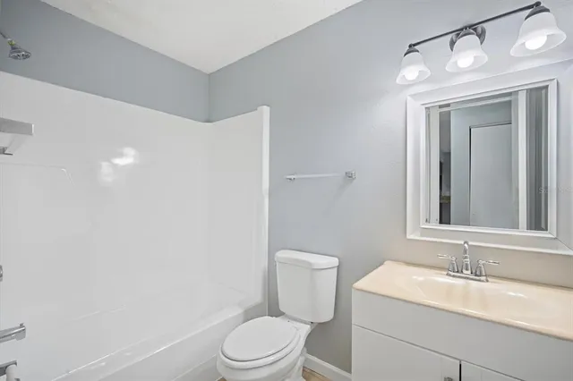 a bathroom with a granite countertop sink mirror vanity and toilet