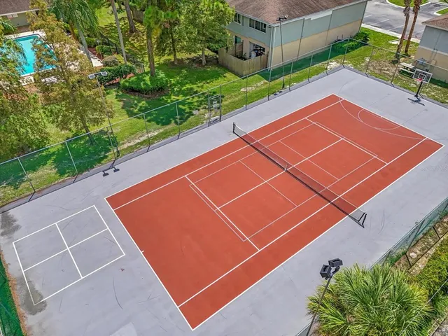 a view of a tennis court with potted plants in front of it