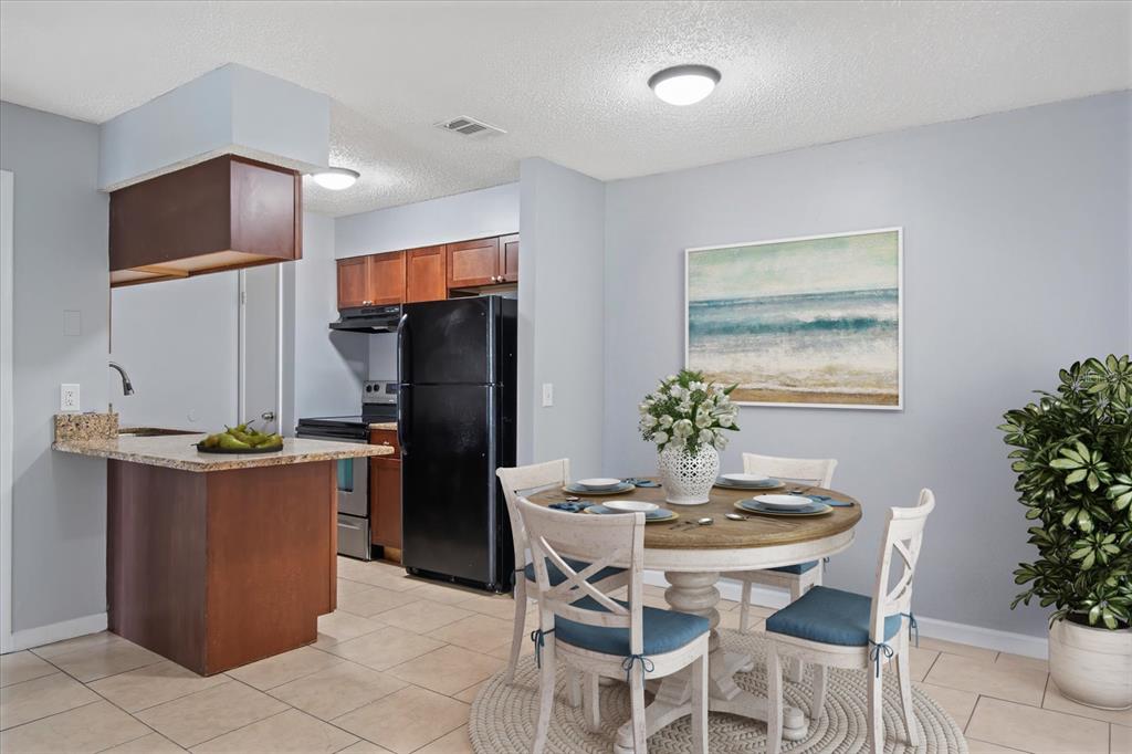 638 Golden Raintree Place Brandon, FL 33510 - Photo 5 of 21 a dining room with stainless steel appliances kitchen island granite countertop a table chairs and a refrigerator