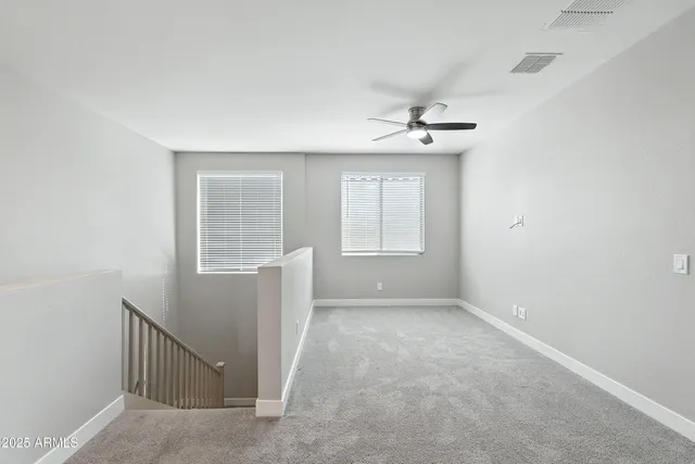 an empty room with windows and fan