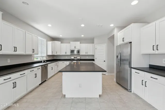 a kitchen with kitchen island granite countertop a sink a counter top space and stainless steel appliances