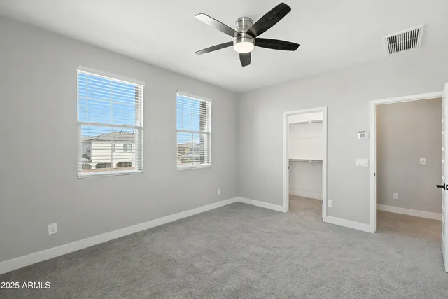 an empty room with closet and a ceiling fan