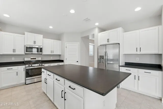 a kitchen with stainless steel appliances granite countertop a sink a stove a refrigerator and white cabinets