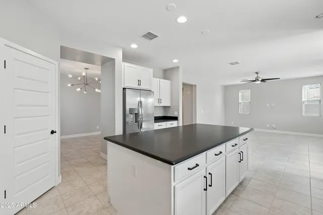 a kitchen with stainless steel appliances granite countertop a refrigerator a sink and white cabinets