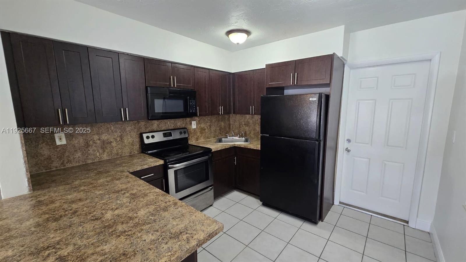 6134 Southwest 40th Court Miramar, FL 33023 - Photo 10 of 15 a kitchen with granite countertop a refrigerator and a stove top oven