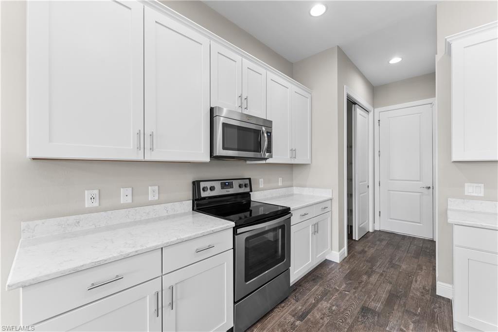 4711 Abaca Circle Naples, FL 34119 - Photo 11 of 32 a kitchen with white cabinets and stainless steel appliances