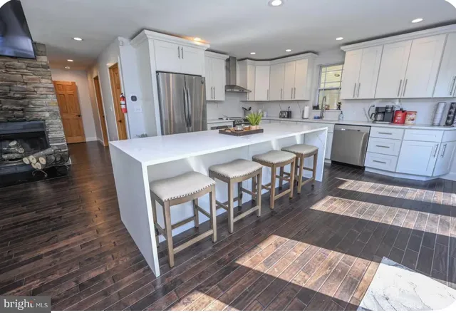 a kitchen with stainless steel appliances kitchen island granite countertop a refrigerator a stove a sink dishwasher and a dining table with wooden floor