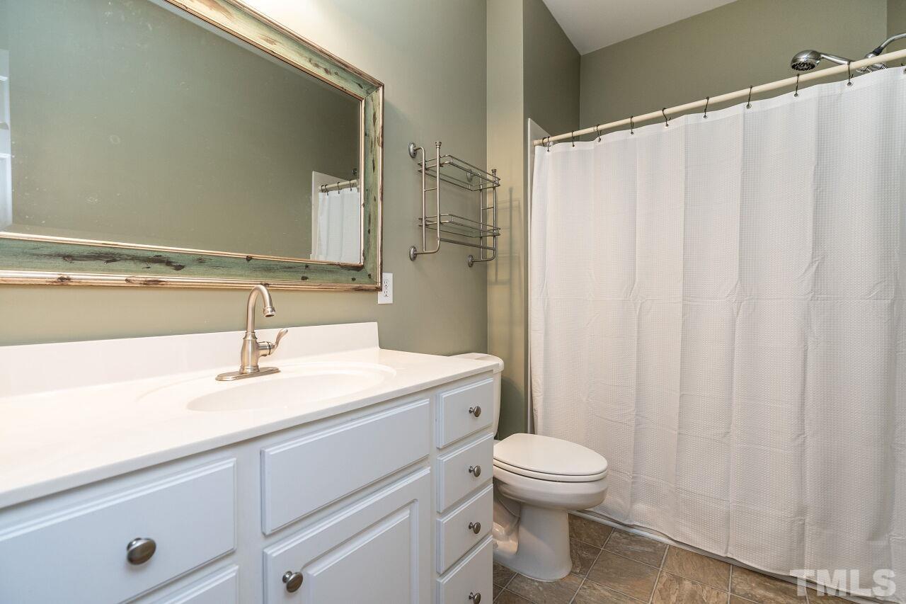 4131 Pearces Road Zebulon, NC 27597 - Photo 17 of 31 a bathroom with a sink a toilet and a mirror