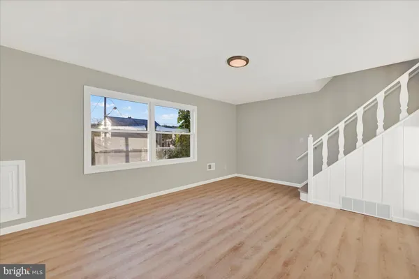a view of an empty room with wooden floor and stairs