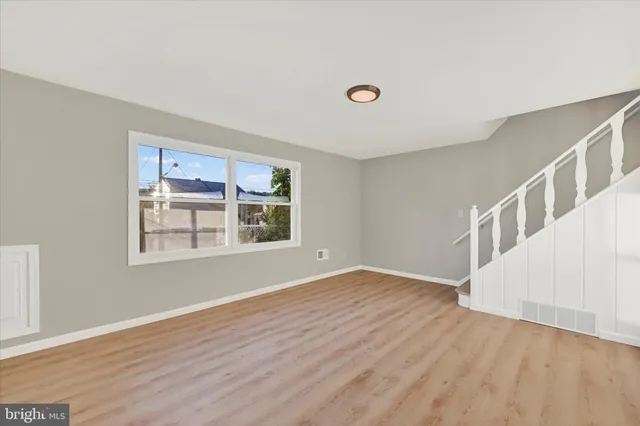 a view of an empty room with wooden floor and stairs