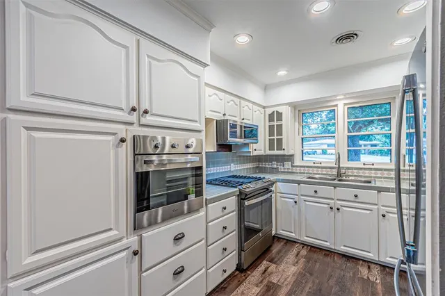 a kitchen with stainless steel appliances granite countertop white cabinets and window
