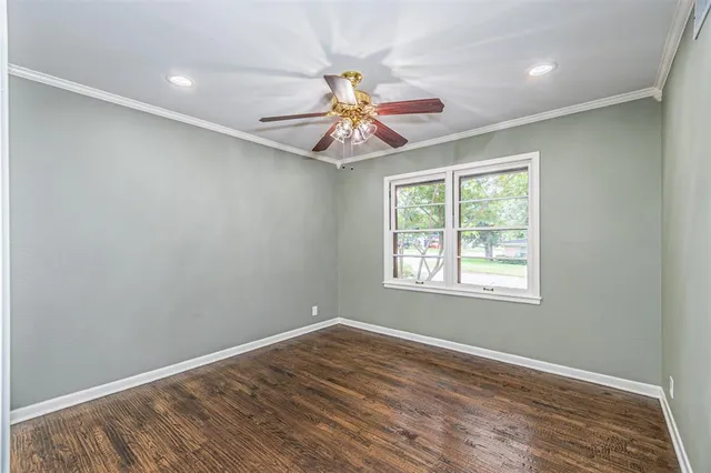a view of an empty room with window and wooden floor