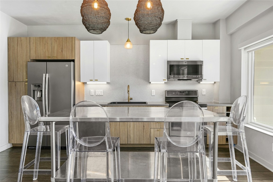 a kitchen with stainless steel appliances a dining table chairs and granite counter tops