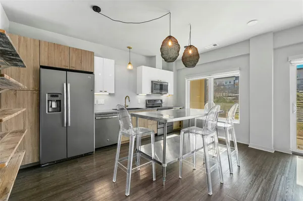 a kitchen with stainless steel appliances a dining table chairs and wooden floor
