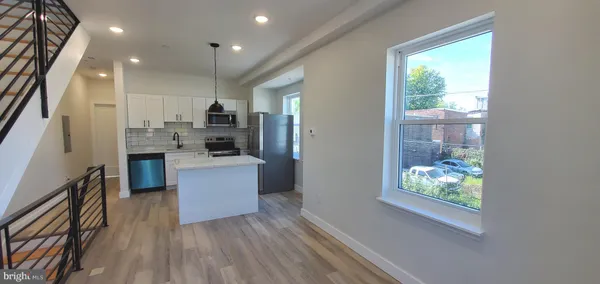 a kitchen with kitchen island wooden floors appliances and furniture