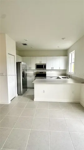 a large kitchen with stainless steel appliances granite countertop a stove a sink and a refrigerator
