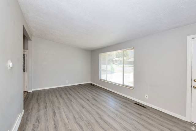 1272 Cook Street Ogden, UT 84404 - Photo 9 of 58 Spacious room featuring wood-finish flooring, light gray wall paint, and a large window with horizontal blinds