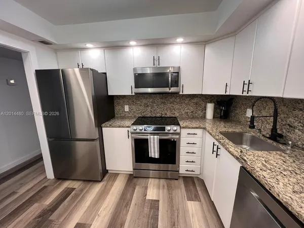 a kitchen with a sink a refrigerator and a stove top oven