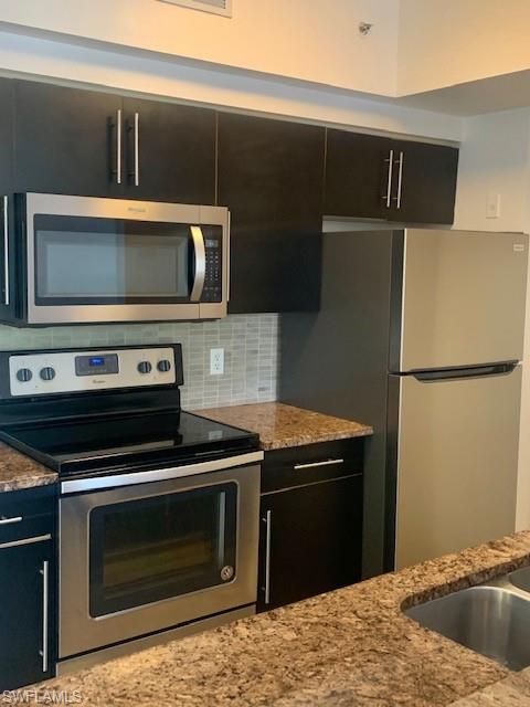 1210 Reserve Way, Unit 9203 Naples, FL 34105 - Photo 2 of 18 a kitchen with a stove and a microwave
